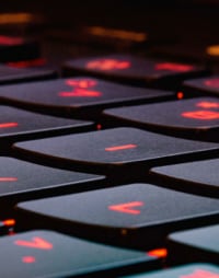 Close-up of a backlit mechanical keyboard with red illumination on the keys, showcasing a modern and sleek design.